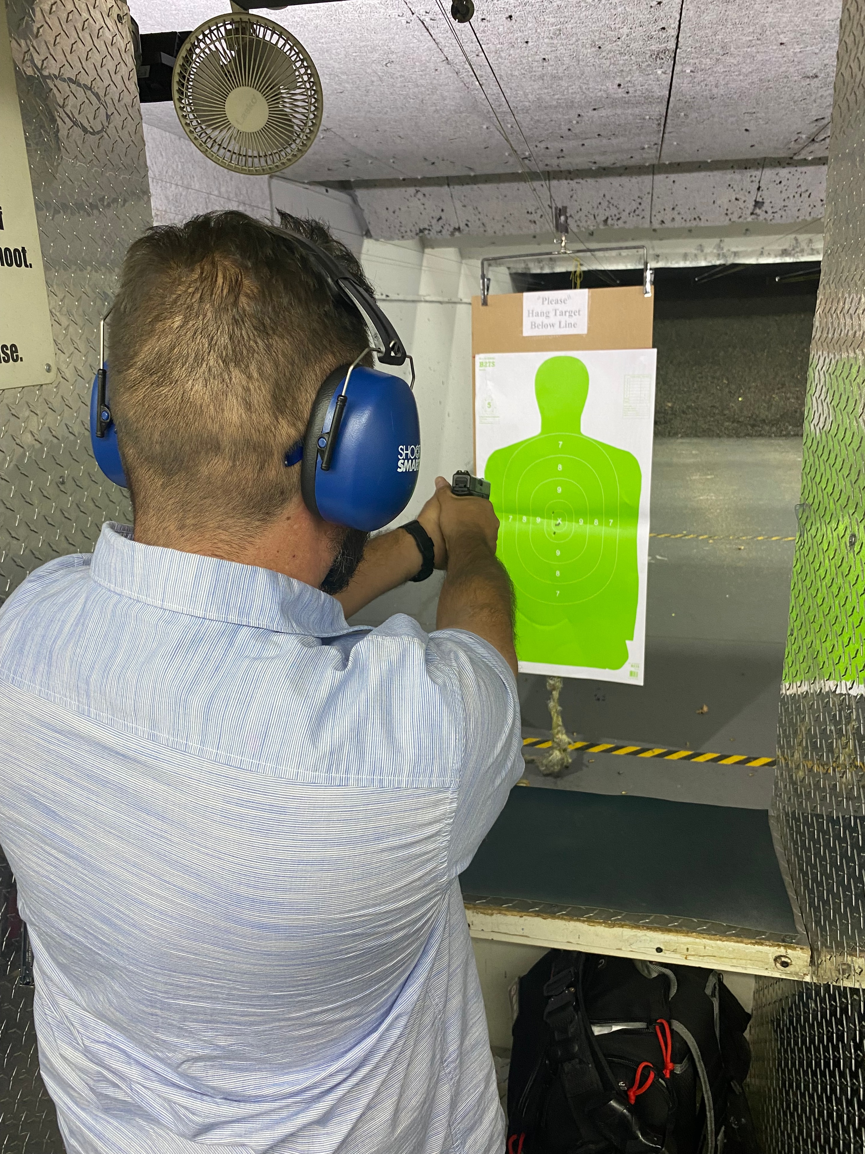 Trainee aiming at green silhouette target during firearms drill